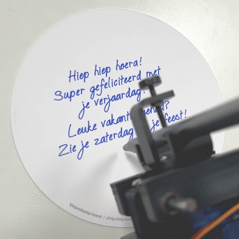 schrijfrobot niko schrijft met pen persoonlijke boodschap op ronde wenskaart