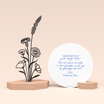 luxe geboorte cadeau met bloemenboeket illustratie in houten standaard en door schrijf-robot geschreven ronde wenskaart in houten blokje