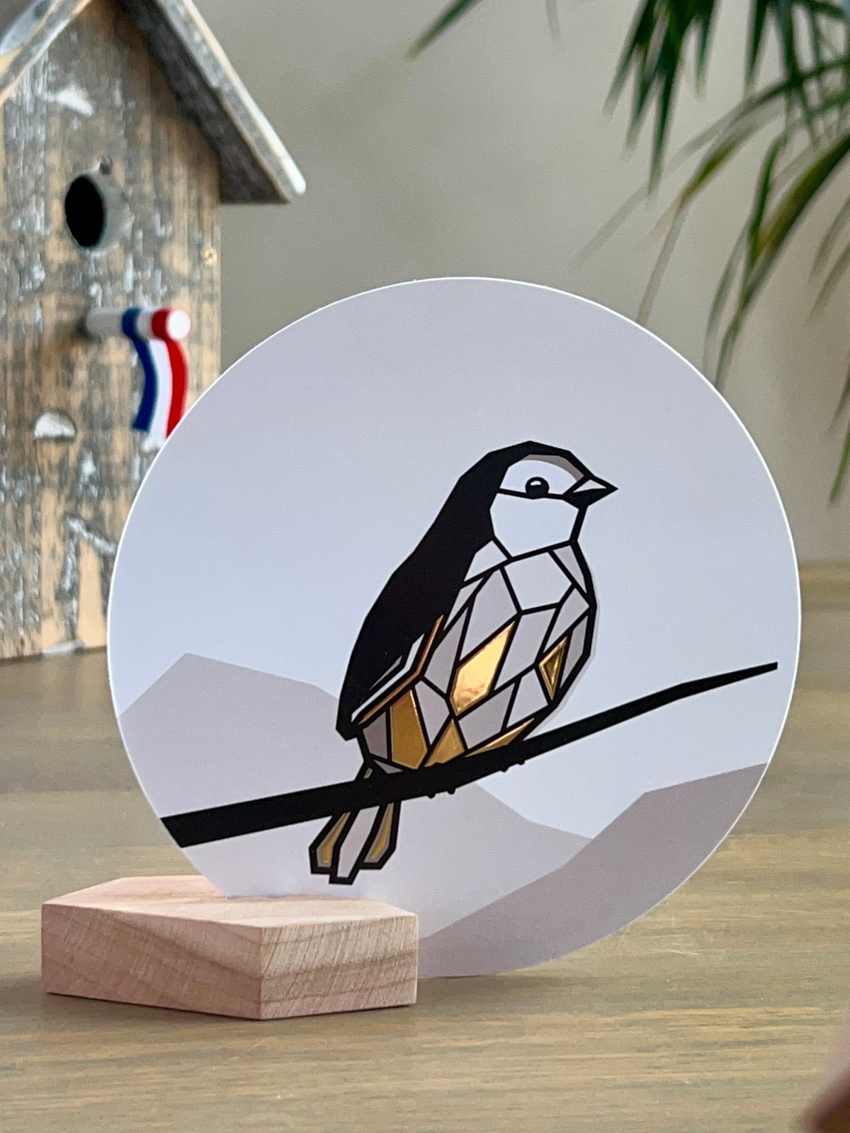 Ronde kaart met huismus met gouden veren in een houten kaarthouder blokje