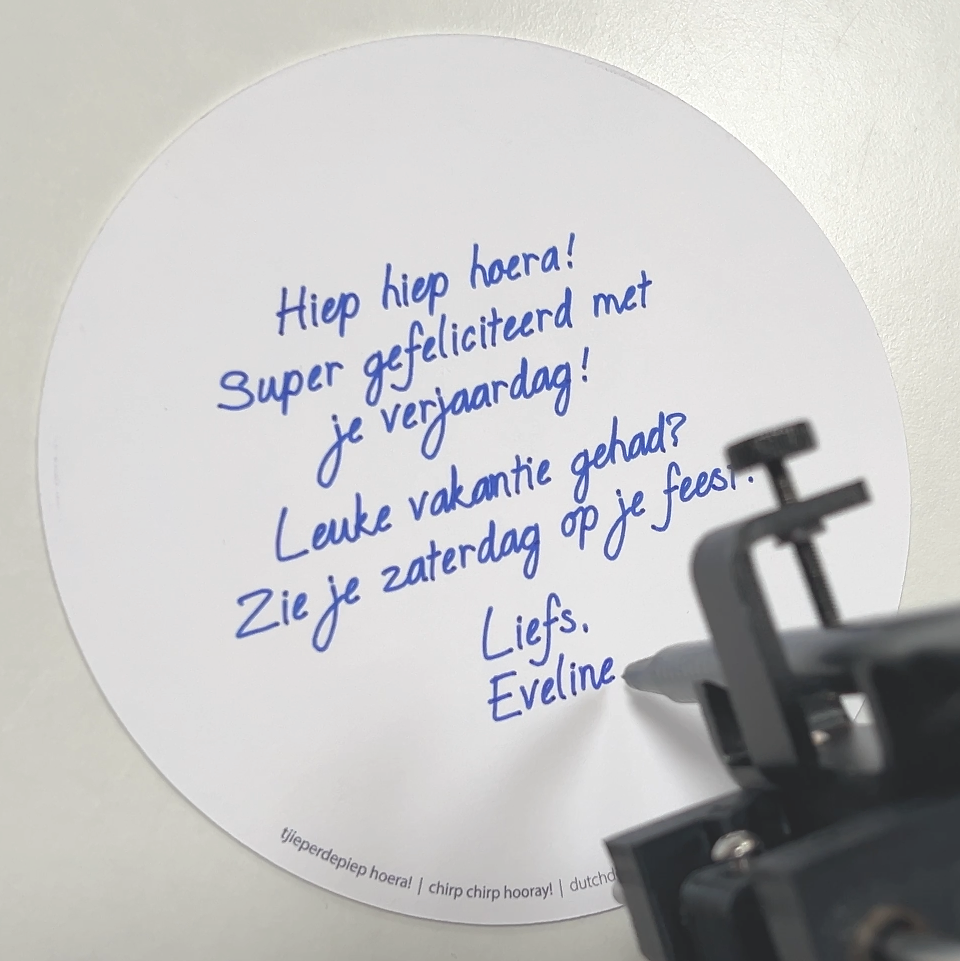 door schrijfrobot met pen geschreven verjaardagstekst op ronde kaart