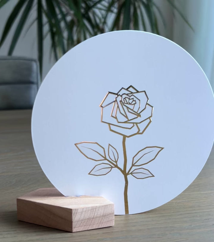 Witte ronde wenskaart in een houten houdertje met een gouden abstracte roos